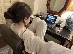 a woman sitting at a desk in front of a laptop computer with her legs crossed