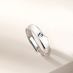 a white gold wedding ring with the letter k on it's side, sitting on a plain surface