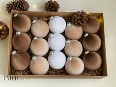 an open box filled with eggs and pine cones on top of a white tablecloth