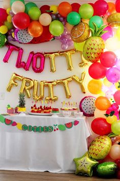 there is a table with balloons and fruit on it