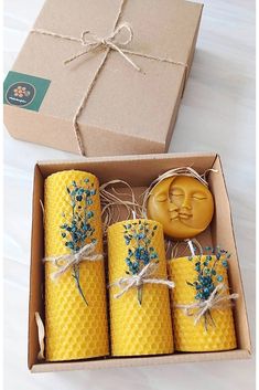 four beeswax candles in a box with a wax stamp on the front and blue flowers on the outside