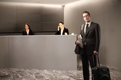 a man in a suit and tie standing next to a counter with luggage on it