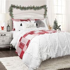 a bed with white and red comforter in a bedroom next to a christmas tree