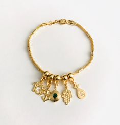 "18k gold filled charm bracelet, number 13, dollar sign, cz eye, hamsa hand, money bag. the charms are moving around the bracelet. 7.5\" long for good luck, money, protection, prosperity.. 18k gold filled pulsera de buena suerte. numero 13, signo del dolar, cz ojo, mano de fatima, bolsa del dinero. para prosperidad, dinero, proteccion, buena suerte. 7.5 \" largo los charm se mueven alrededor de la pulsera." Gold Spiritual Charm Bracelet With Dangling Charms, Gold Spiritual Charm Bracelet For Good Luck, Good Luck Bracelet, Number 13, Dollar Sign, Charms Bracelet, Protection Bracelet, Evil Eye Pendant, Money Bag