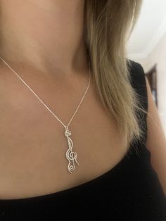 a woman wearing a necklace with a musical note on it