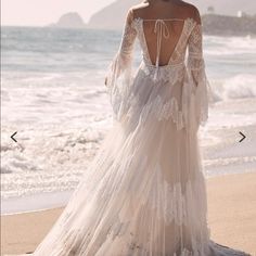 a woman standing on top of a beach next to the ocean wearing a white dress