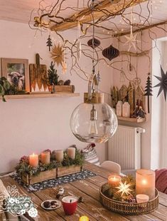 a wooden table topped with lots of candles next to a christmas decoration hanging from the ceiling