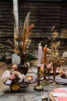 a table topped with lots of different types of flowers and candles on top of it