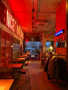 the inside of a restaurant with tables, chairs and neon signs on the wall above them