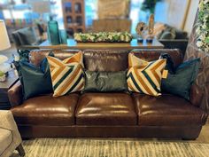 a brown leather couch sitting in a living room next to a table with flowers on it