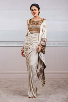 Ivory draped saree in metallic foil jersey embellished with print and crystal transfers.
Component: 1
Embellished
Neckline: Round
Sleeve Length: Asymmetric
Fabric: Foil Jersey
Color: White
Flared sleeve
Embellished bodice
Print detail
Sheer back
Closure: Back zip - Aza Fashions Saree Gowns, Saree Women, Draped Saree, White Foil, Fashion Illustrations Techniques, Saree For Women, White Flares, Drape Saree, Tarun Tahiliani