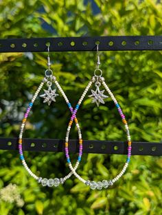 -Handmade native beaded drop hoop earrings with silver fishhook earring backs -Shades of purple, blue, pink and orange seed beads with silver accents -4 inches long, 2 inches wide -All pieces of jewelry are made with TLC by myself, Demiree! Dangle Earrings With Silver Beads For Festivals, Silver Beaded Dangle Earrings For Festivals, Festival Dangle Earrings With Silver Beads, Bohemian Multicolor Star-shaped Jewelry, Silver Beaded Earrings With Colorful Beads For Festival, Southwestern Style Beaded Dangle Hoop Earrings, Silver Beaded Dangle Hoop Earrings, Silver Southwestern Beaded Earrings With Ear Wire, Southwestern Silver Beaded Earrings With Ear Wire