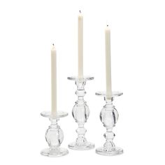 three clear glass candlesticks with one candle in the middle