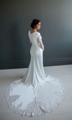 a woman in a white wedding dress is looking off into the distance with her back to the camera