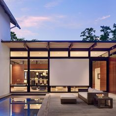 an outdoor living area with couches, tables and large screen on the outside wall