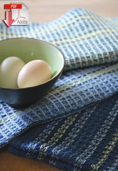 two eggs in a bowl on a blue and green towel