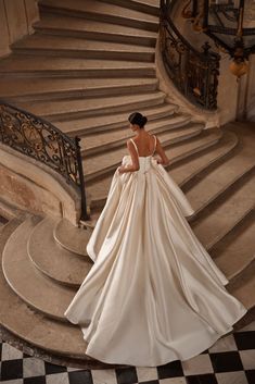 a woman in a wedding dress standing on some stairs with her back to the camera