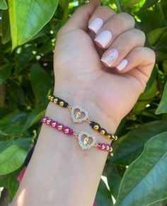 a woman's hand with two bracelets on her wrist, one is gold and the other is red