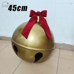 a large metal ball with a red bow on it's top sitting on the floor