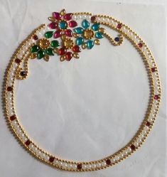 three strand necklace with multicolored stones and pearls on white paper, top view