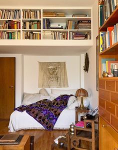 a bed sitting under a book shelf filled with books