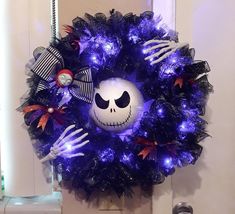 a halloween wreath decorated with purple lights and skeleton hands