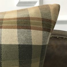 a plaid pillow sitting on top of a brown couch