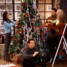 friends decorating a christmas tree on the set of friends and family tv show in their living room