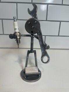 a metal figurine holding a wrench on top of a white tile wall