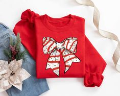 Christmas Coquette Bow Sweatshirt, Santa Claus Bow Shirt, Red Bow Christmas T-Shirt, Holiday Xmas Apparel, Christmas Women Sweater Hello! Thank you for supporting small businesses. My main priority here is the satisfaction of my customers. High quality and super soft, comfortable shirt. Made with special quality vinyl and pressed with a first class heat press. 𝗛𝗢𝗪 𝗧𝗢 𝗢𝗥𝗗𝗘𝗥 𝟏. Please, Check and Review all Listing Photos. 𝟐. Select Your Size and Color from drop down menus. 𝟑. Choose Y Red Long Sleeve Christmas T-shirt, Red Festive Holiday Top, Red Holiday Tops For Festive Occasion, Red Holiday Sweatshirt For Winter, Red Casual Holiday Sweatshirt, Casual Red Holiday Sweatshirt, Casual Red Sweatshirt For Holidays, Red Christmas Holiday Sweatshirt, Red Winter Sweatshirt As Gift