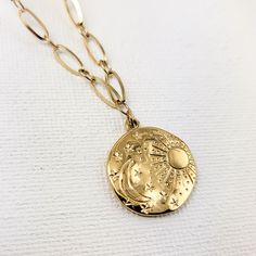 Our celestial-inspired necklace set features two intricately crafted pieces adorned with a beautifully engraved scene of the moon, stars, and sun. Crafted from stainless steel and plated in 18k gold, this 2 in one necklace offers a modern layered look. Embrace celestial charm with these versatile piece or layer together with more necklaces for a truly bold statement. Material: Stainless Steel - 18k Gold plated Size: can be extended to approx. 17 in. Weight: 4 oz Celestial Round Pendant Jewelry With Tarnish Resistance, Celestial Jewelry With Tarnish Resistant Round Pendant, Celestial Style Gold Jewelry With Round Pendant, Celestial Round Pendant Jewelry Tarnish Resistant, Gold Jewelry With Moon Charm In Metal, Adjustable Celestial Engraved Jewelry, Symbolic Gold Jewelry With Moon Phase, Celestial Gold Plated Tarnish Resistant Jewelry, Celestial Style Round Metal Pendant Jewelry