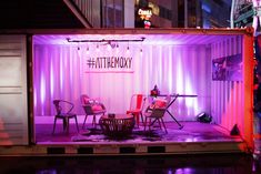 a stage set up with chairs and tables in front of a shipping container at night