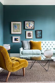 a living room with blue walls and pictures on the wall, two yellow chairs in front of a white couch