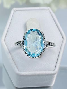 Custom Aqua-Blue Gemstone Ring Made To Order:   Setting Description #70 Here we have an Edwardian reproduction ring in sterling silver filigree with a perfect Simulated/Man-made blue aquamarine gemstone solitaire (or a Natural 6ct to 6.5ct Sky Blue Topaz also available, see last picture in set), all other pictures are the simulated aquamarine option. The full cut oval gem is 14mm in length and 10mm in width. This ring also sits 7mm off the finger. The inside of the band is marked 925 for sterlin Classic Light Blue Topaz Ring For Formal Occasions, Classic Light Blue Topaz Ring, Vintage Blue Topaz Ring With Diamond Cut, Classic Light Blue Oval Jewelry, Classic Light Blue Topaz Gemstone Ring, Formal Oval Topaz Ring With Filigree, Antique Blue Topaz Ring Hallmarked, Classic Blue Round Cut Topaz Ring, Classic Blue Topaz Ring Round Cut