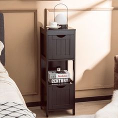 a small black shelf with magazines on it in a bedroom next to a white bed