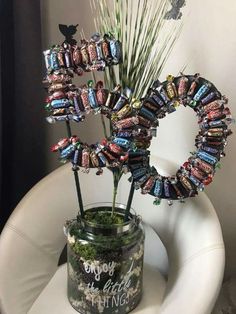 a jar filled with candy sitting on top of a white chair next to a plant