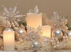 some candles are sitting on a table with snowflakes and other decorations around them