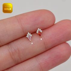 the tiny diamond earrings are being held in someone's hand with gold lettering on it