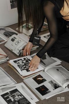 a woman is sitting on the floor with many books in front of her and reaching for something