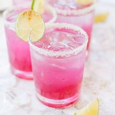 three glasses filled with pink lemonade and garnished with limes on the rim