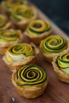 several small pastries with spiral designs on them sitting on a cutting board next to each other