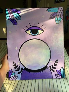 someone is holding up a purple painting with an eye and stars in the sky on it