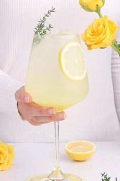 a person holding a glass filled with lemonade