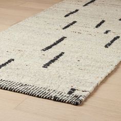 a rug with black and white designs on the bottom is laying on a wooden floor