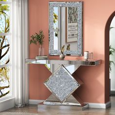 a console table with a mirror and vase on it in front of a pink wall