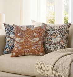 three pillows on a couch in front of a window