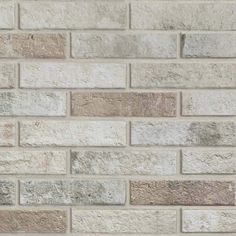 a white brick wall is shown with grey and brown bricks on the bottom right hand corner