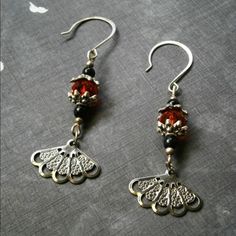 Filigree Fan Cathedral crystals Silver earrings Simply lovely metal stamped fans with Tibetan ornate bead caps, gorgeous blood red cathedral Crystal beads with black onyx stone rounds on silver fish hooks. There's a bit of light glare on this but it's all silver despite the gold tone from the light Twisted Seas  Jewelry Earrings Red Cathedral, Earthy Earrings, Sea Jewelry, Fish Hooks, Silver Fish, Black Onyx Stone, Blood Red, Onyx Stone, Simply Lovely