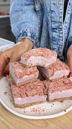 a woman is holding a plate with desserts on it, including raspberry cheesecake