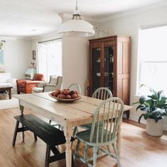 a dining room table with two chairs and a bowl of fruit on top of it